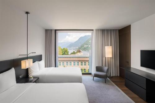 a hotel room with two beds and a large window at Hilton Lake Como in Como
