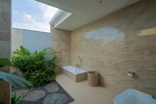 a bathroom with a tub and a toilet and a sink at Suralaya Villas in Ubud