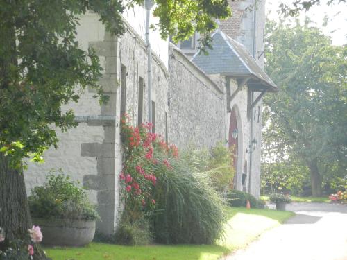 a stone house with pink flowers on the side of it at La tour de la Chapelle in Couthuin