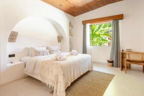a bedroom with a white bed with a table and a window at Harbie Villa in Seminyak