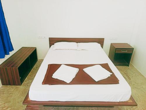 a bedroom with a bed with white sheets and two tables at The Blue Planet Long Island in Middle Andaman