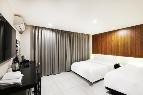 a hotel room with two beds and a television at Selene Hotel in Seoul