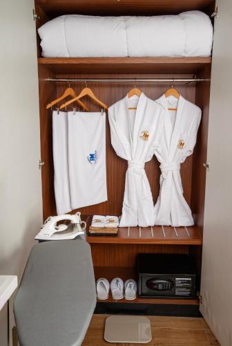 a closet with white shirts and a bed at Nagarjun Resort - Embrace Tranquility Natures Retreat Beyond the City in Kathmandu