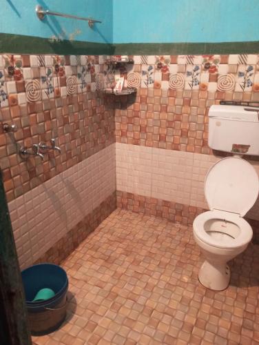 a tiled bathroom with a toilet and a blue bucket at Hotel shiva in Sar