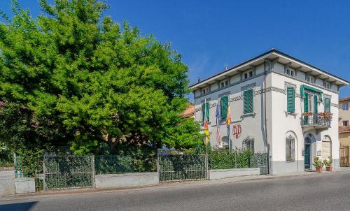 um edifício branco com janelas verdes e uma árvore em B&B La Mimosa em Lucca