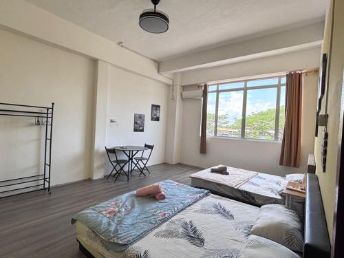 a room with two beds and a table and a window at WAQI Homestay in Miri