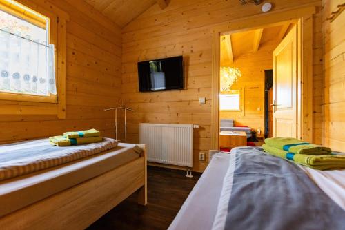 two beds in a wooden room with a tv at Bungalows am Senftenberger See in Großkoschen