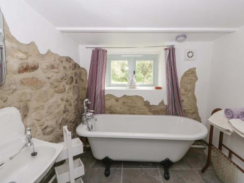 a white bath tub in a bathroom with a stone wall at Rhos Y Clegyrn in Goodwick