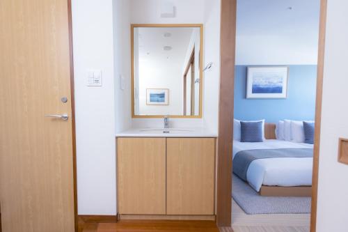 a bathroom with a sink and a bed at Hayama Umino Hotel in Hayama