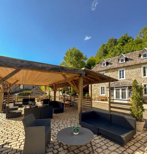 a patio with a wooden pergola and chairs and a table at Solayan Nature & Spa, Piscine Intérieure, Bains Nordiques & Vue Pyrénées in Couledoux