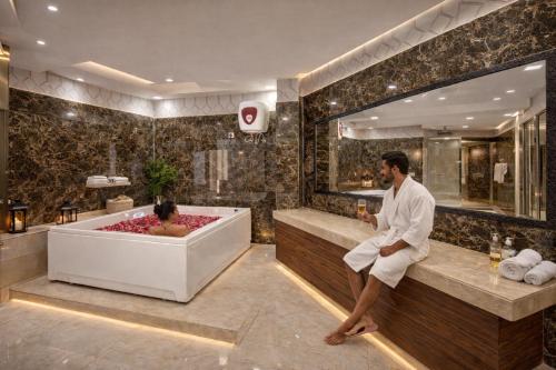 a man sitting in a bath tub in a bathroom at Hotel Radiance Park Delhi Airport in New Delhi