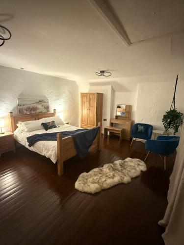 a bedroom with a bed and a blue chair and a rug at Lucy Cross Guest House in Lucy Cross
