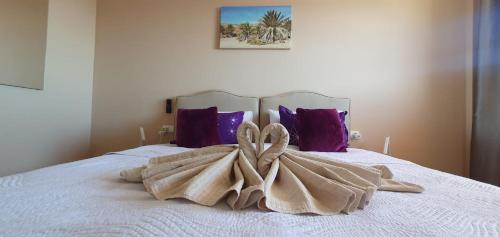 a blanket on a bed with purple pillows at Playa Paraiso-Apartment 4 you in Costa Calma