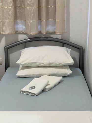 a bed with white pillows and two towels on it at Apartment Sajković in Ugljan