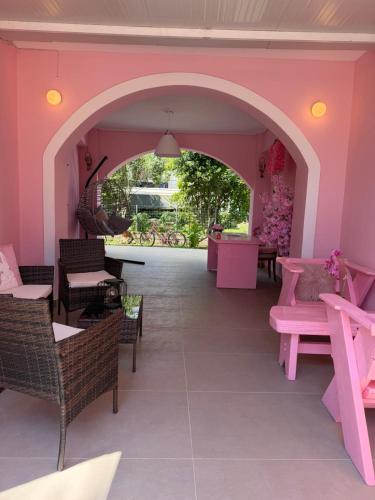 a pink room with chairs and tables and a patio at No Name Apartments in Laganas