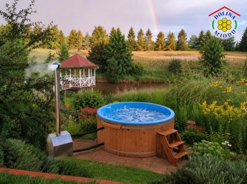 a hot tub in a garden with a rainbow in the background at Dolina Miodu - Agro Kaszuby, Sauna, Balia in Borowina