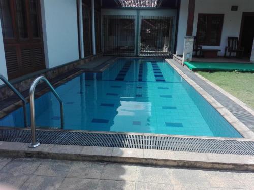 a blue swimming pool with blue tiles in a house at Maple Suite in Kadawata