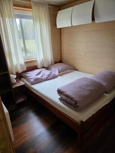 a large bed in a small room with a window at Domek letniskowy - niebieski całoroczny in Stegers