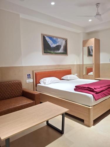 a bedroom with a bed and a couch and a table at Arunachal residency in Dibrugarh