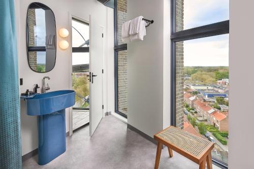 a bathroom with a blue sink and a large window at Hotel Restaurant Grandcafé 't Voorhuys in Emmeloord