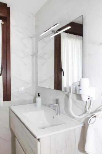 a white bathroom with a sink and a mirror at Apartamentos Los Novalejos in Arnuero