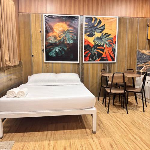 a bedroom with a bed and a table and paintings at La Palma Air'bnb Malaybalay in Casisang