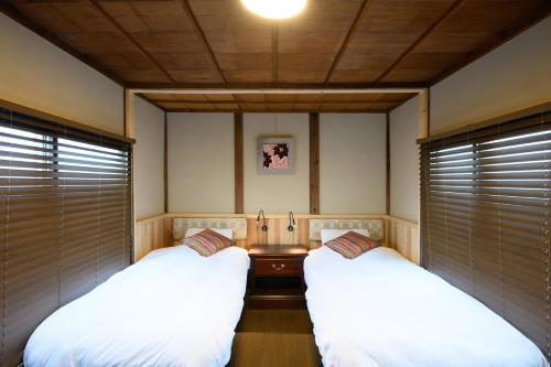 two beds in a room with blinds on the windows at NOW Onomichi in Onomichi