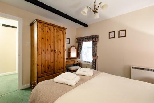 a bedroom with a large bed with two towels at Lupin Cottage in Wooler