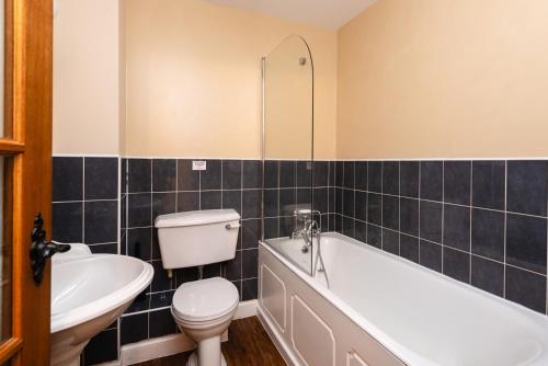a bathroom with a toilet and a tub and a sink at Lupin Cottage in Wooler