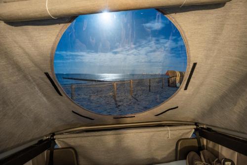 a view of the beach through a round window at Schlafstrandkorb Nr 5 in Kellenhusen