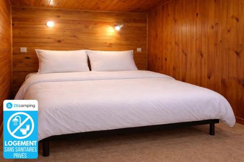 a bed in a room with a wooden wall at ZEcamping 3 étoiles familial avec Piscine et Bar-restaurant in Saint-Honoré-les-Bains