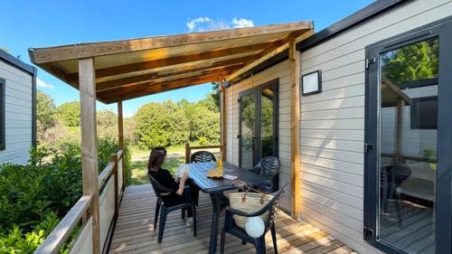a woman sitting at a table on a deck at ZEcamping 3 dog friendly piscine dans le parc régional du Verdon in Valensole