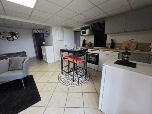 a kitchen with a counter and a table in it at Châtel-guyon : Appart cosy avec place de parking et piscine près des thermes in Châtel-Guyon