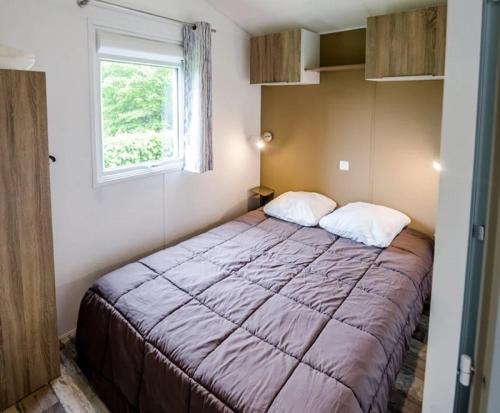 a bedroom with a bed in a room with a window at ZEcamping 4 pet friendly piscine couverte et parcours Fitness in Pressignac