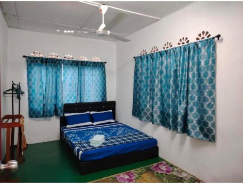 a bedroom with a blue bed and blue curtains at Homestay Bakti in Bandar  Pusat Jengka