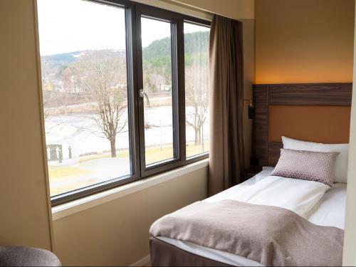 a bedroom with a bed and a large window at Quality Hotel Grand Kongsberg in Kongsberg