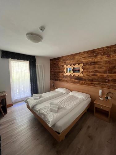 a bedroom with a large bed and a wooden wall at Hotel Garni Relax in Fai della Paganella