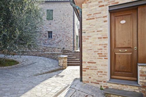 a brick building with a wooden door on the side at Casa Oliva borgo del Benessere delle Marche in Bargni