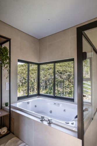 a bath tub in a bathroom with windows at Terra Alta Chalé in Gonçalves