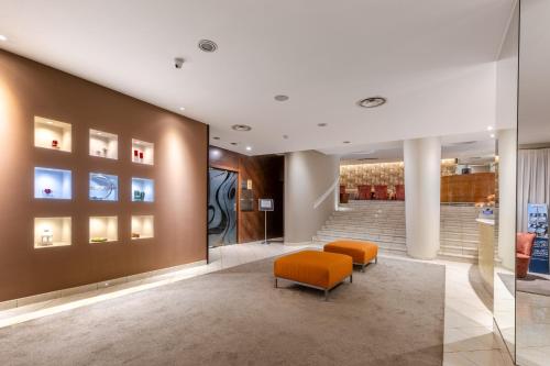 a lobby with two orange chairs and a staircase at Aston Hotel in Pino Torinese
