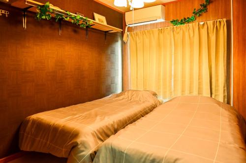 a bedroom with two beds and a window with plants at ブルク井尻 Brug ijiri in Itazuke