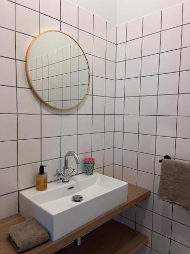 a white bathroom with a sink and a mirror at Gastenverblijf spoarsicht in Lioessens