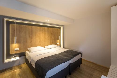 a bedroom with a large bed with a wooden headboard at M Hotel in Ljubljana