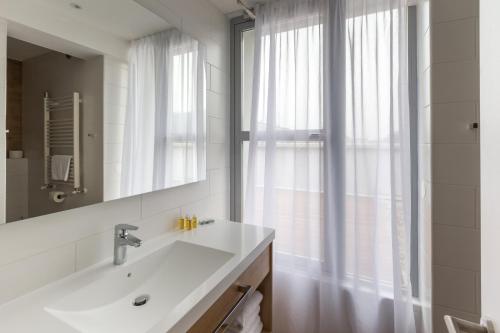 a bathroom with a sink and a mirror and a window at M Hotel in Ljubljana