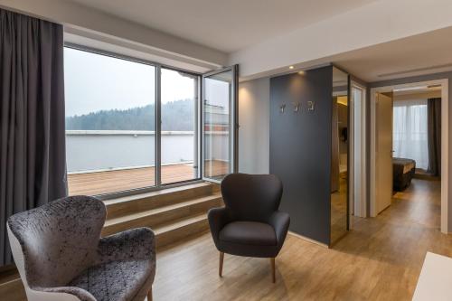 a living room with a chair and a large window at M Hotel in Ljubljana