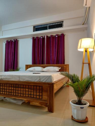 a bedroom with a bed with purple curtains and a plant at Homestay in Tezpur
