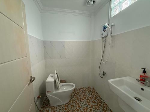 a white bathroom with a toilet and a sink at Mango Bungalow in Kaôh Rŭng (3)