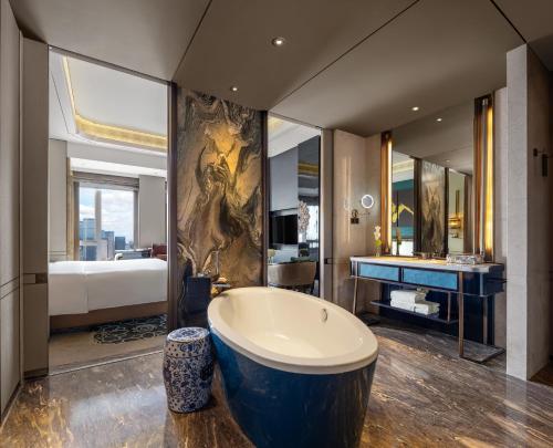 a large bathroom with a tub and a bed at Wanda Reign Chengdu in Chengdu
