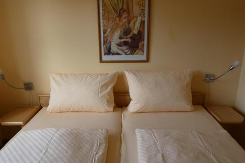 a bed with two pillows and a picture on the wall at Pension Altes Posthaus in Dangast