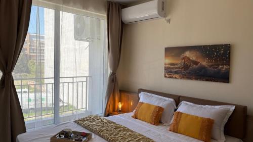 a bedroom with a bed and a large window at Krasi Apartments in Perla Complex in Pomorie
